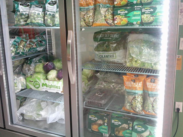 Produce which is mostly salads in a fridge.